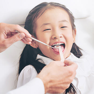 Una niña con la boca abierta mientras el dentista trabaja