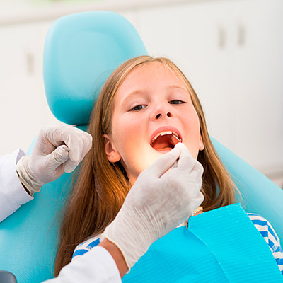 El dentista iluminando la boca de una niña